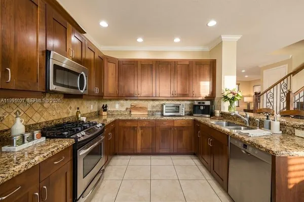 a kitchen with stainless steel appliances granite countertop wooden cabinets a stove top oven a sink and dishwasher