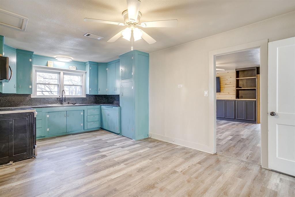 206 Bateman Street Meridian, TX 76665 - Photo 13 of 26 a kitchen with kitchen island granite countertop a sink cabinets and wooden floor