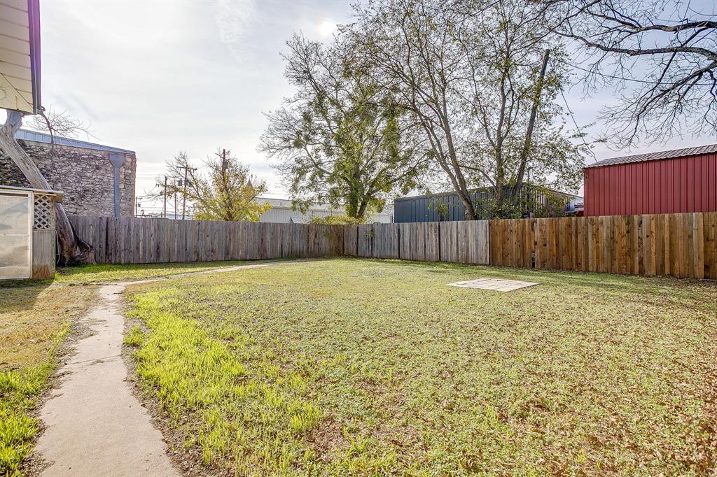 206 Bateman Street Meridian, TX 76665 - Photo 24 of 26 a view of a backyard with large tree and wooden fence