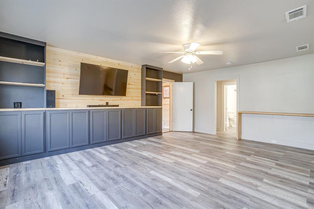 206 Bateman Street Meridian, TX 76665 - Photo 3 of 26 Unfurnished living room featuring light wood-style flooring, built in features, wood walls, and a ceiling fan