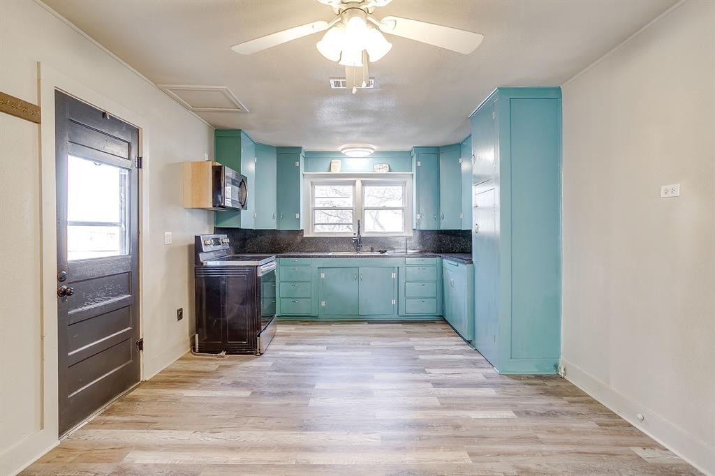 206 Bateman Street Meridian, TX 76665 - Photo 7 of 26 Kitchen with dark countertops, electric range, light wood-style flooring, stainless steel microwave, and blue cabinets