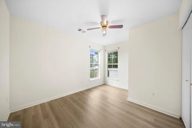 an empty room with wooden floor closet and windows