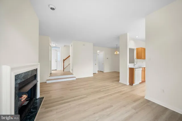 a view of an empty room with wooden floor and a fireplace