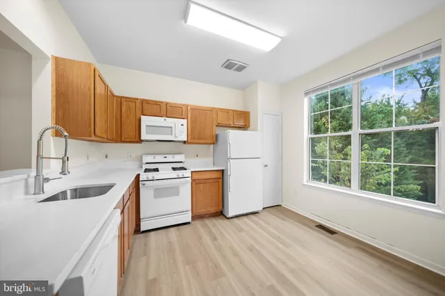 a kitchen with a sink wooden cabinets and a window