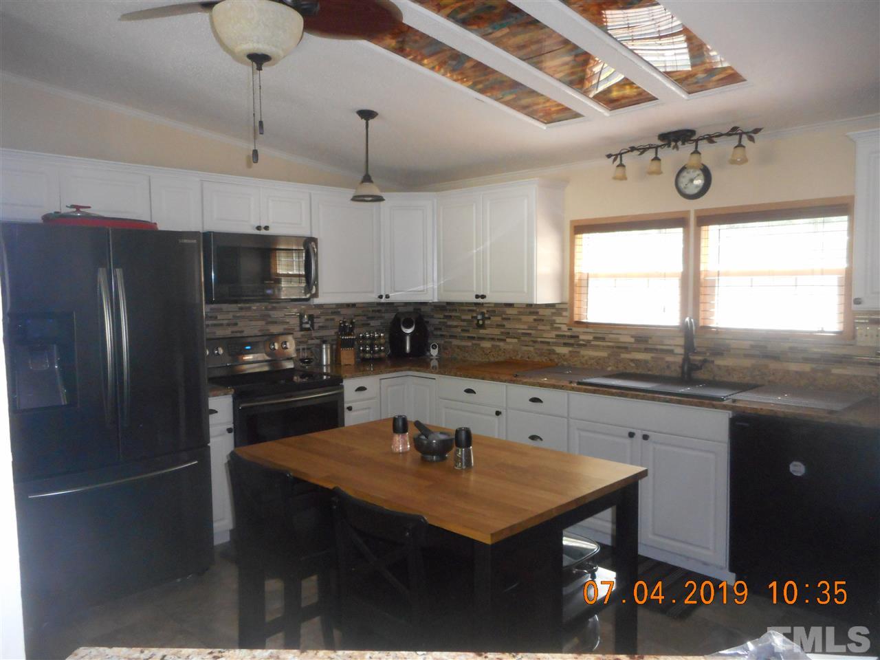 301 Mountain Ridge Road Rougemont, NC 27572 - Photo 16 of 22 a kitchen with stainless steel appliances a sink a stove a refrigerator cabinets and a dining table