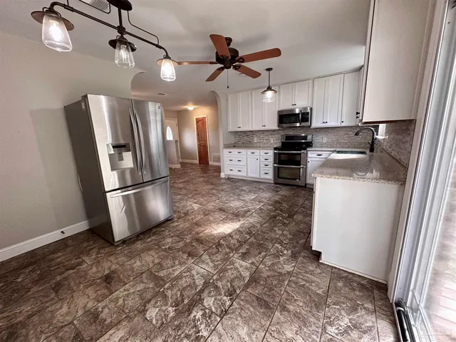 a kitchen with stainless steel appliances granite countertop a refrigerator a stove a sink and a refrigerator