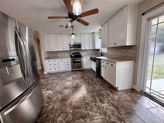 a kitchen with stainless steel appliances granite countertop a refrigerator a stove and a sink