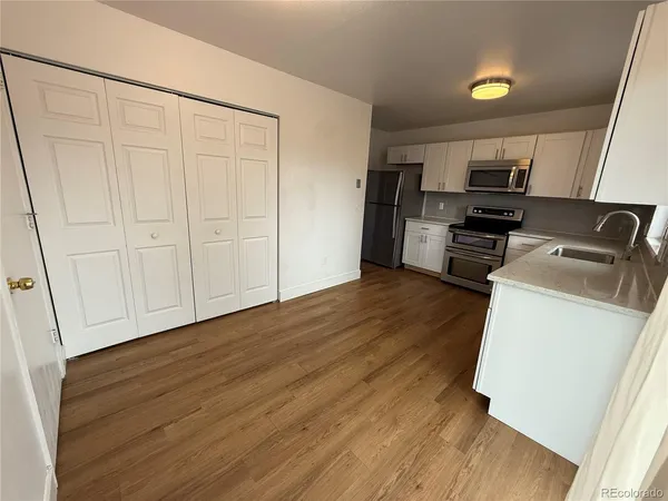 a view of a kitchen with wooden floor and electronic appliances