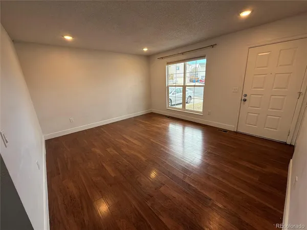 an empty room with wooden floor and windows