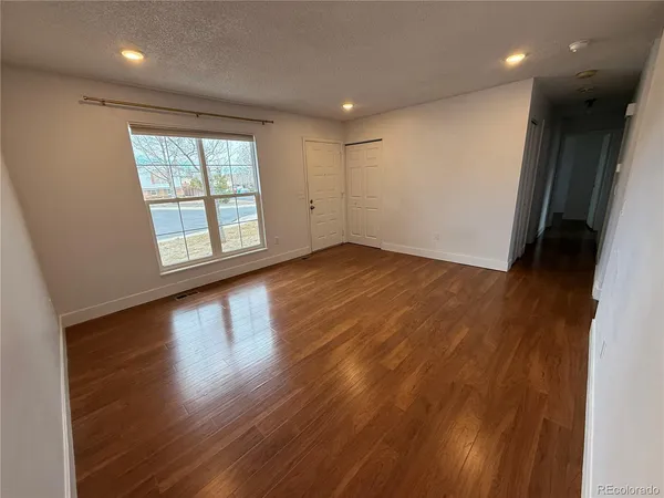 an empty room with wooden floor and windows