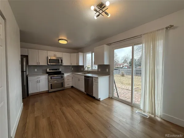 a kitchen with wooden floors and appliances