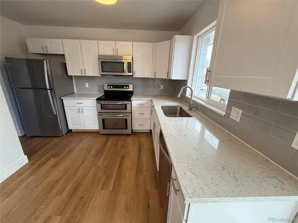 a kitchen with granite countertop a refrigerator stove and sink