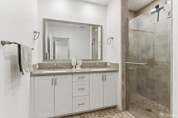 a bathroom with a granite countertop sink two mirror and shower