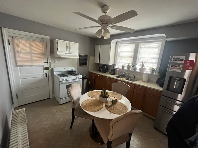 a kitchen with stainless steel appliances a sink a stove a refrigerator cabinets and dining table