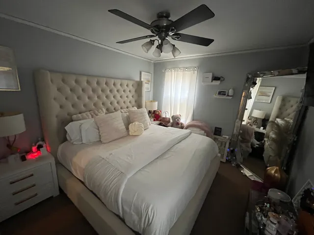 a large bed sitting in a bedroom next to a window and a chandelier
