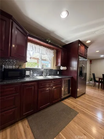 a kitchen with stainless steel appliances granite countertop wooden cabinets a stove a sink and a large window