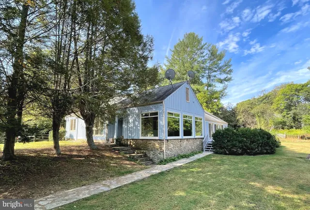 an empty room with wooden floor fireplace and chandelier