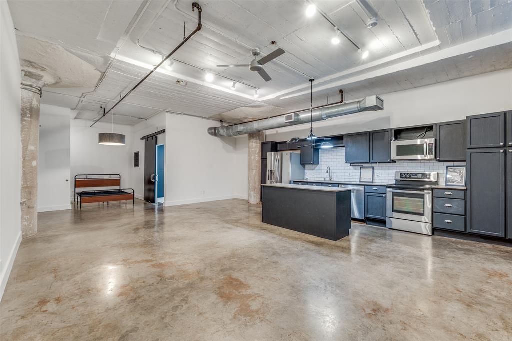 1122 Jackson Street, Unit 922 Dallas, TX 75202 - Photo 11 of 25 a large kitchen with stainless steel appliances kitchen island granite countertop lots of counter space and a sink