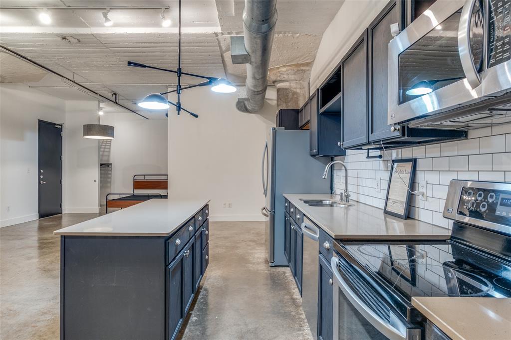 1122 Jackson Street, Unit 922 Dallas, TX 75202 - Photo 22 of 25 a kitchen with stainless steel appliances granite countertop a sink a stove and a wooden floors