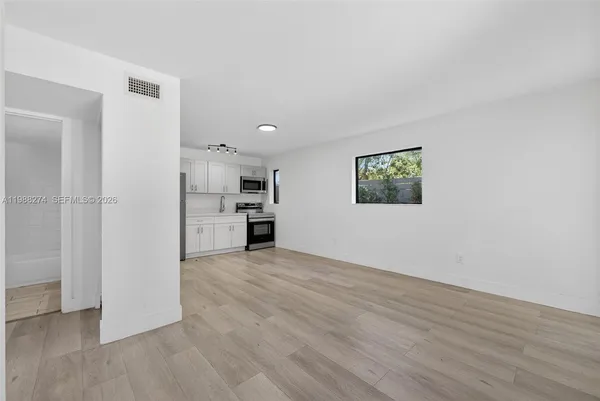 a view of a kitchen with wooden floor and a refrigerator
