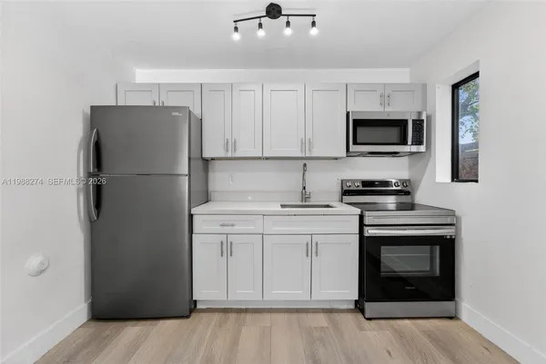 a kitchen with a sink stainless steel appliances and white cabinets