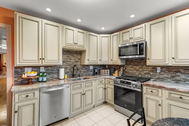 a kitchen with stainless steel appliances granite countertop white cabinets a stove a sink and dishwasher