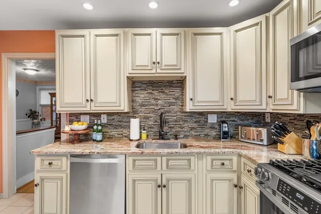 a kitchen with stainless steel appliances granite countertop a stove a sink and white cabinets