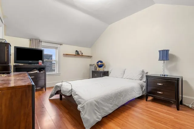 a bedroom with a bed and a flat tv screen on a dresser