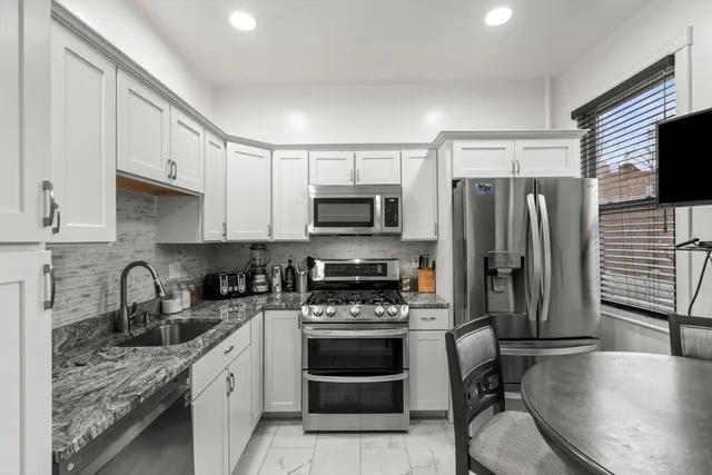a kitchen with stainless steel appliances a stove a sink a refrigerator a stove a microwave and cabinets