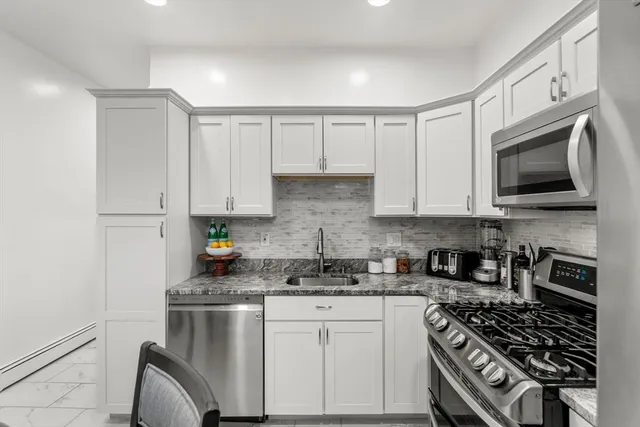 a kitchen with stainless steel appliances granite countertop a stove a sink and a microwave