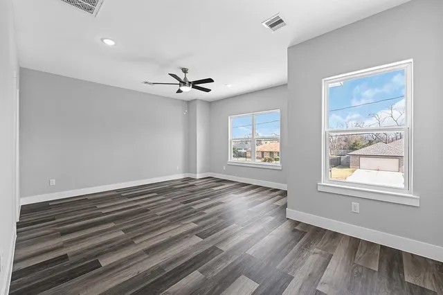 a view of an empty room with a window and wooden floor