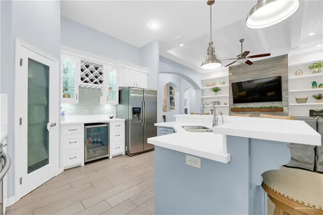 a large kitchen with a stove a sink dishwasher a refrigerator and a fireplace with wooden floor