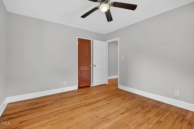 an empty room with wooden floor and ceiling fan