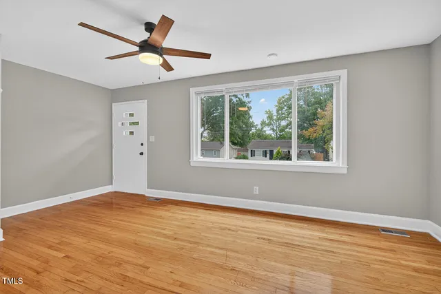 a view of empty room with wooden floor and fan