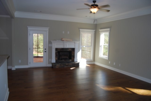 10 Laurel Ridge Forsyth, GA 31029 - Photo 4 of 23 an empty room with wooden floor a chandelier fan and a fireplace