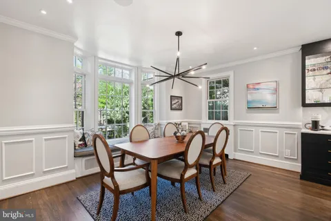 a dining room with wooden floor a chandelier a glass table and chairs