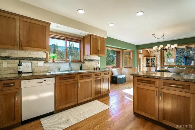 a kitchen with stainless steel appliances granite countertop wooden cabinets a sink a stove a dining table and chairs