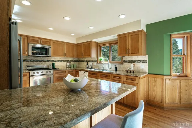 a kitchen with stainless steel appliances granite countertop a sink a stove top oven a counter space and cabinets