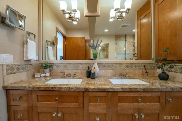 a bathroom with a granite countertop double vanity sink and a mirror