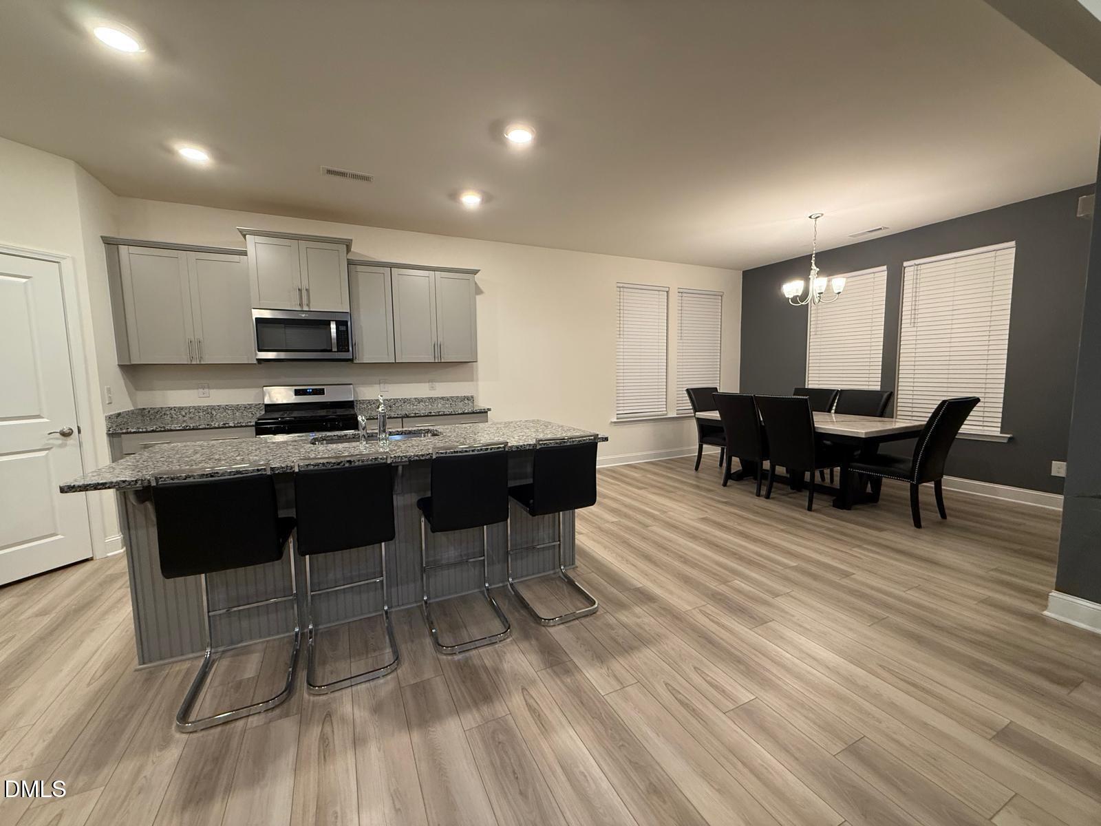 64 Nailsworth Street Angier, NC 27501 - Photo 5 of 14 a kitchen with stainless steel appliances kitchen island granite countertop a dining table chairs and a refrigerator