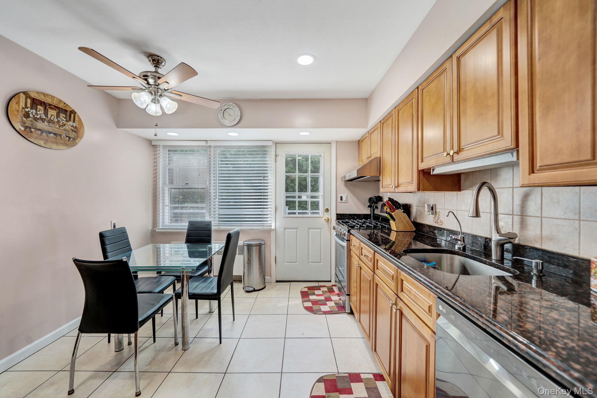 1 Wayland Road Plainview, NY 11803 - Photo 12 of 28 Kitchen with dark stone counters, decorative backsplash, stainless steel appliances, light tile patterned floors, and a ceiling fan