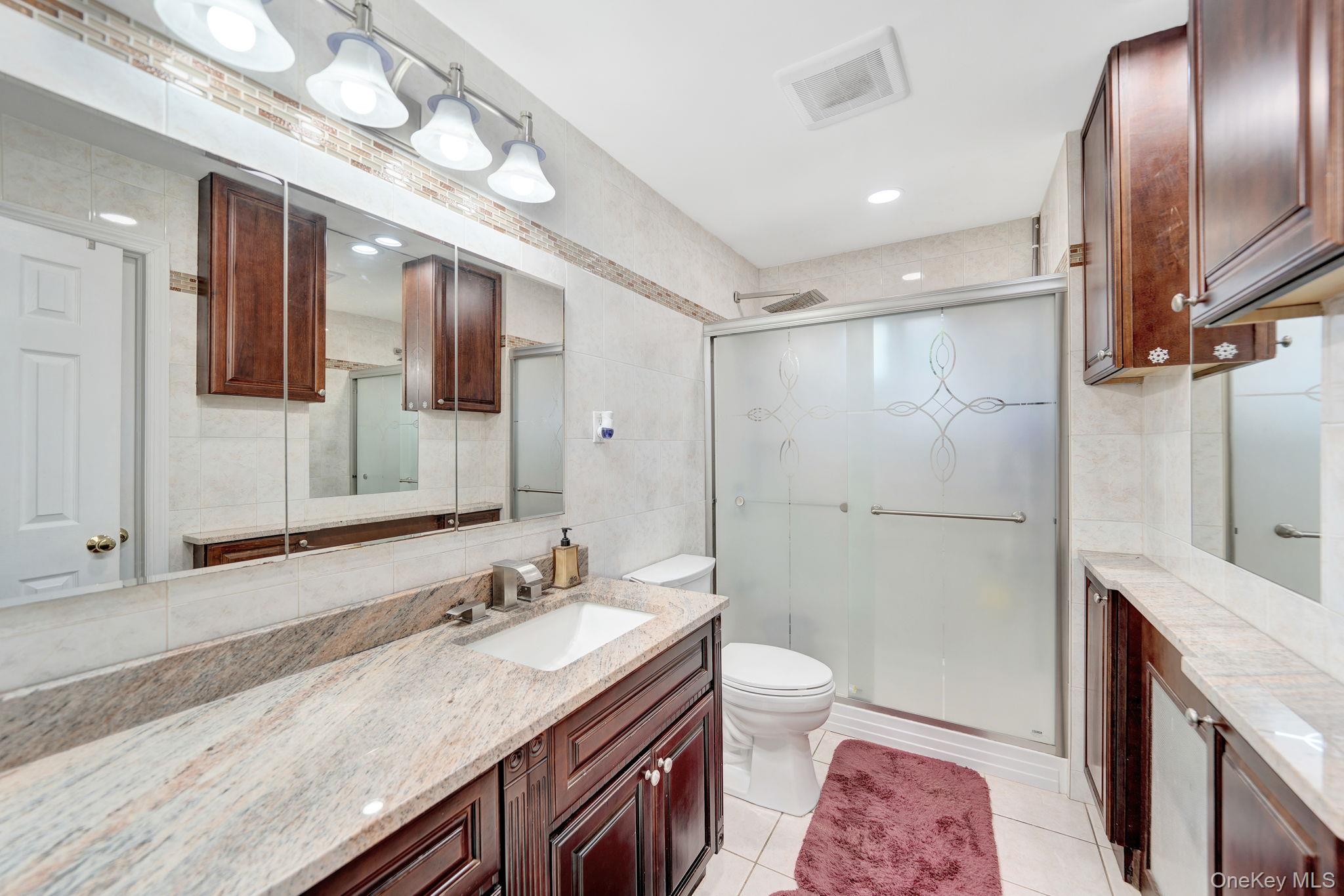 1 Wayland Road Plainview, NY 11803 - Photo 17 of 28 Bathroom with tile walls, light tile patterned floors, vanity, a shower stall, and decorative backsplash
