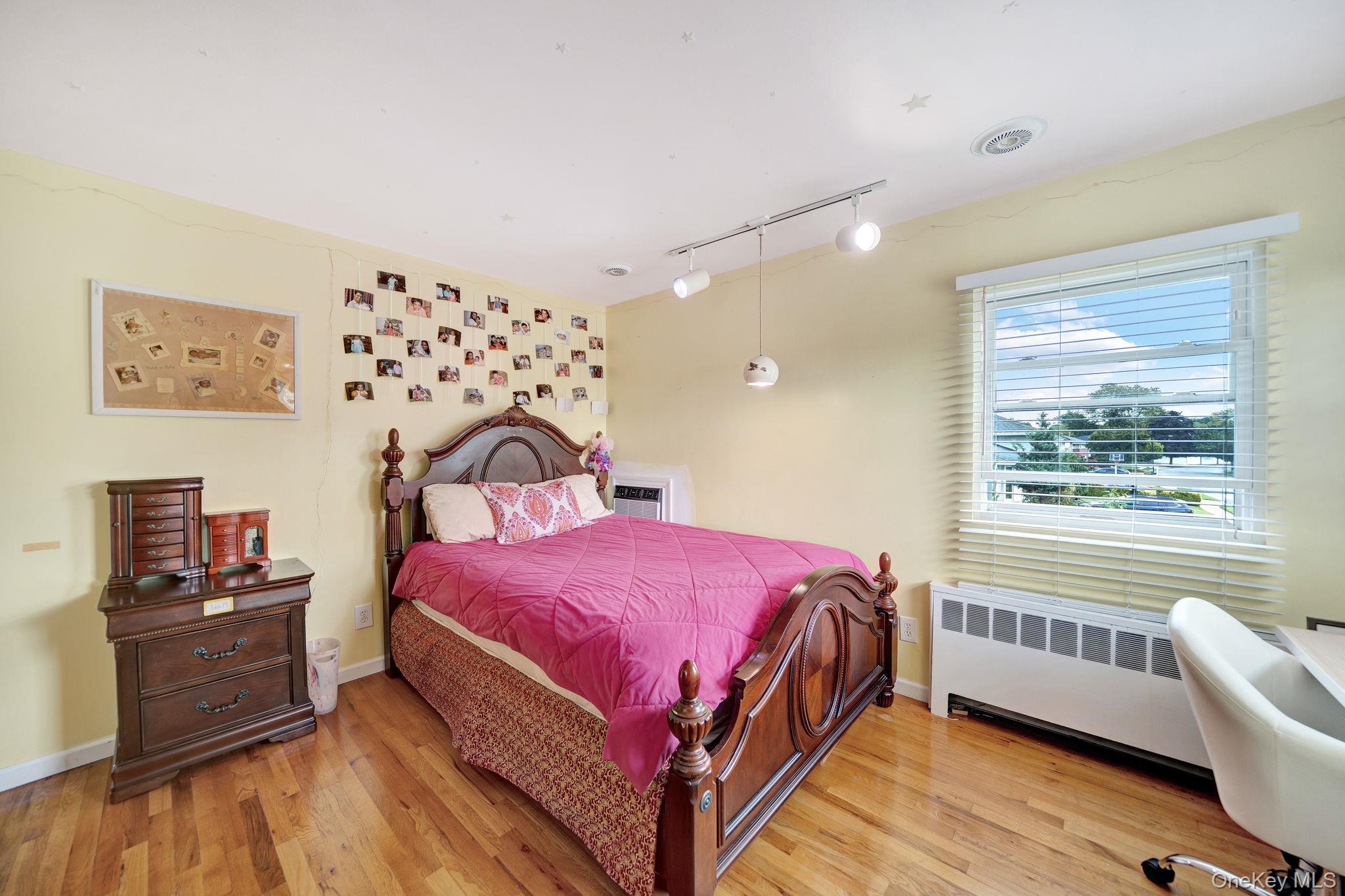 1 Wayland Road Plainview, NY 11803 - Photo 20 of 28 Bedroom with radiator, rail lighting, light wood-type flooring, and an AC wall unit