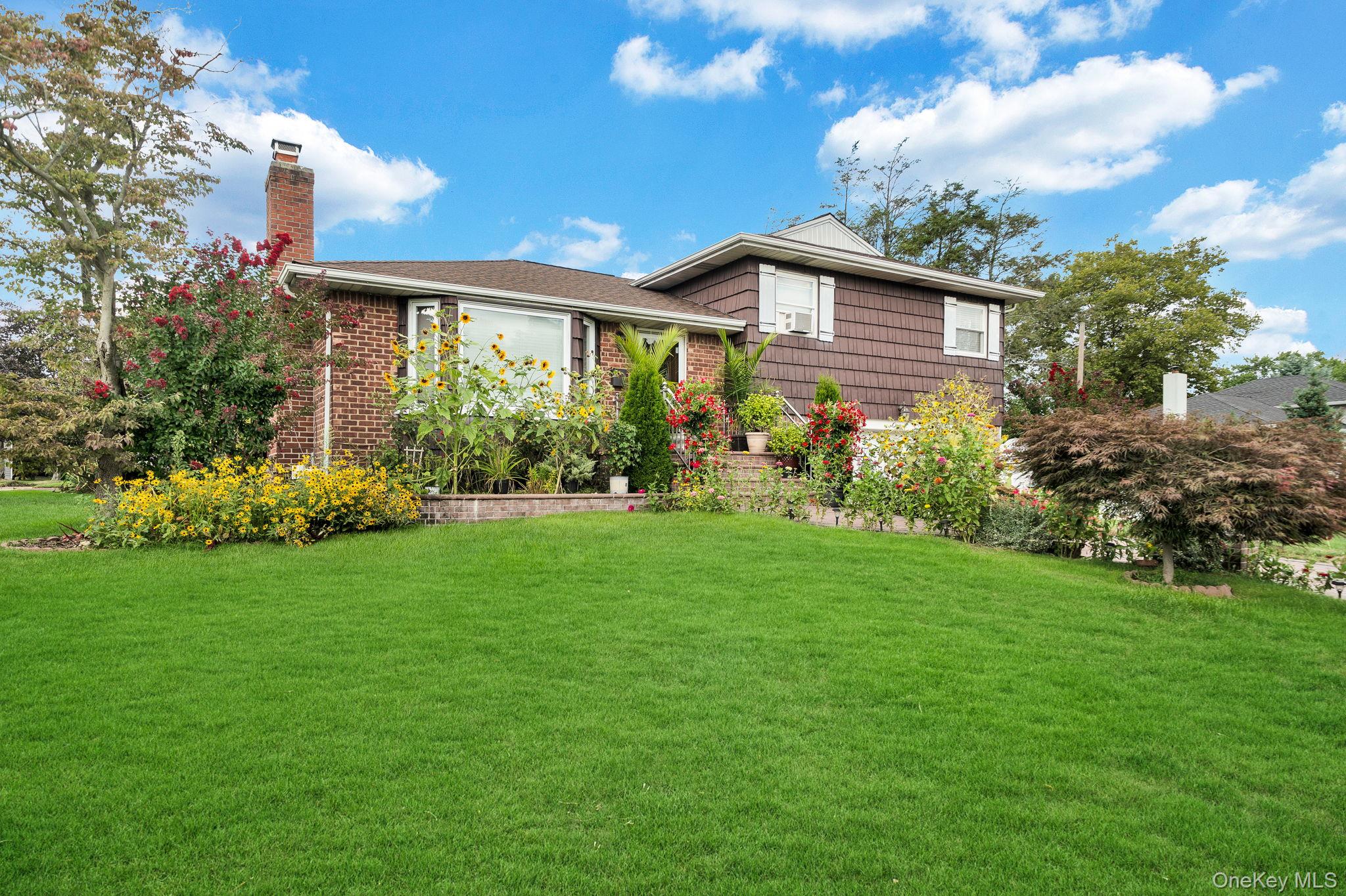 1 Wayland Road Plainview, NY 11803 - Photo 2 of 28 Tri-level home featuring a front yard and a chimney