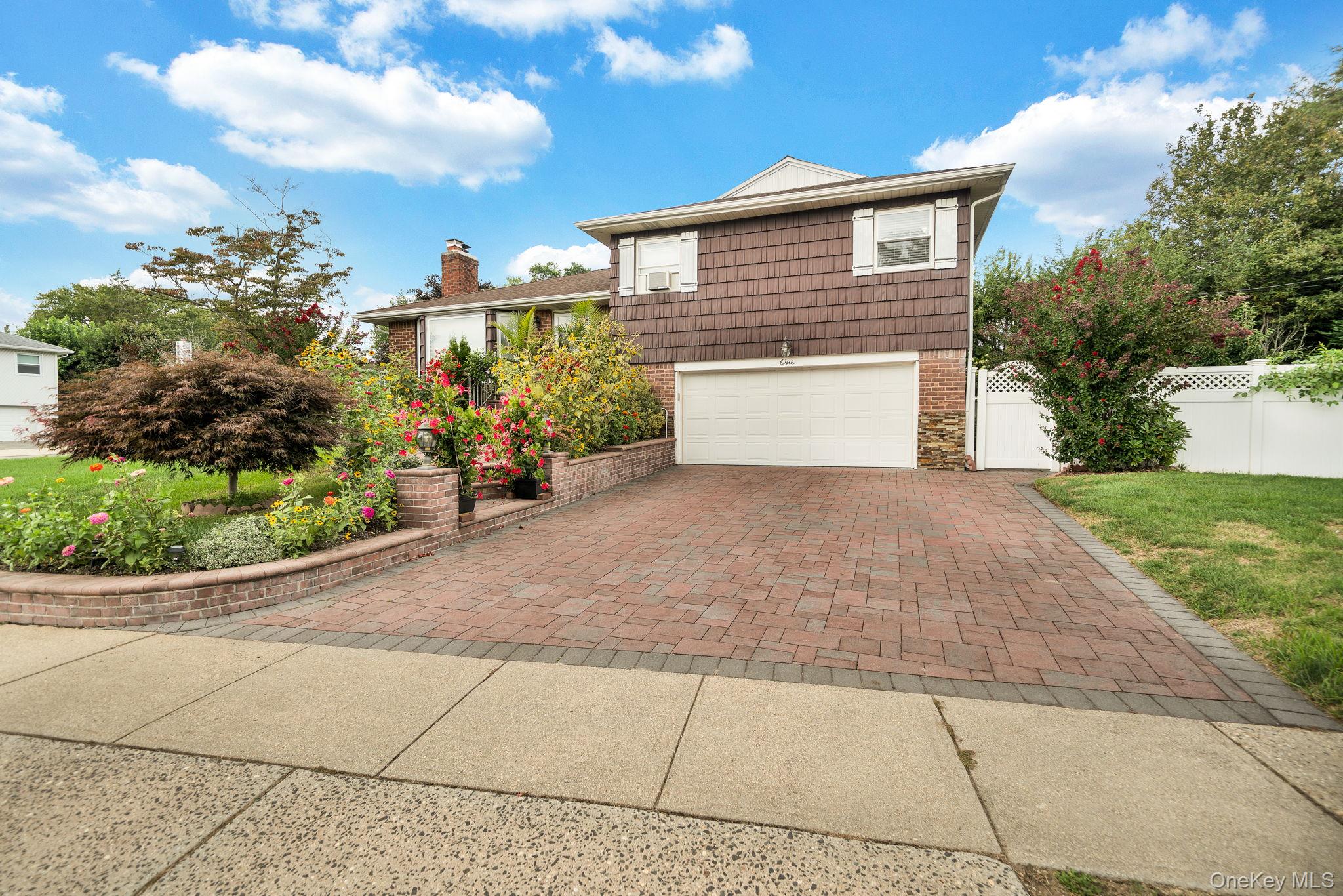 1 Wayland Road Plainview, NY 11803 - Photo 3 of 28 Tri-level home featuring decorative driveway, an attached garage, and a chimney