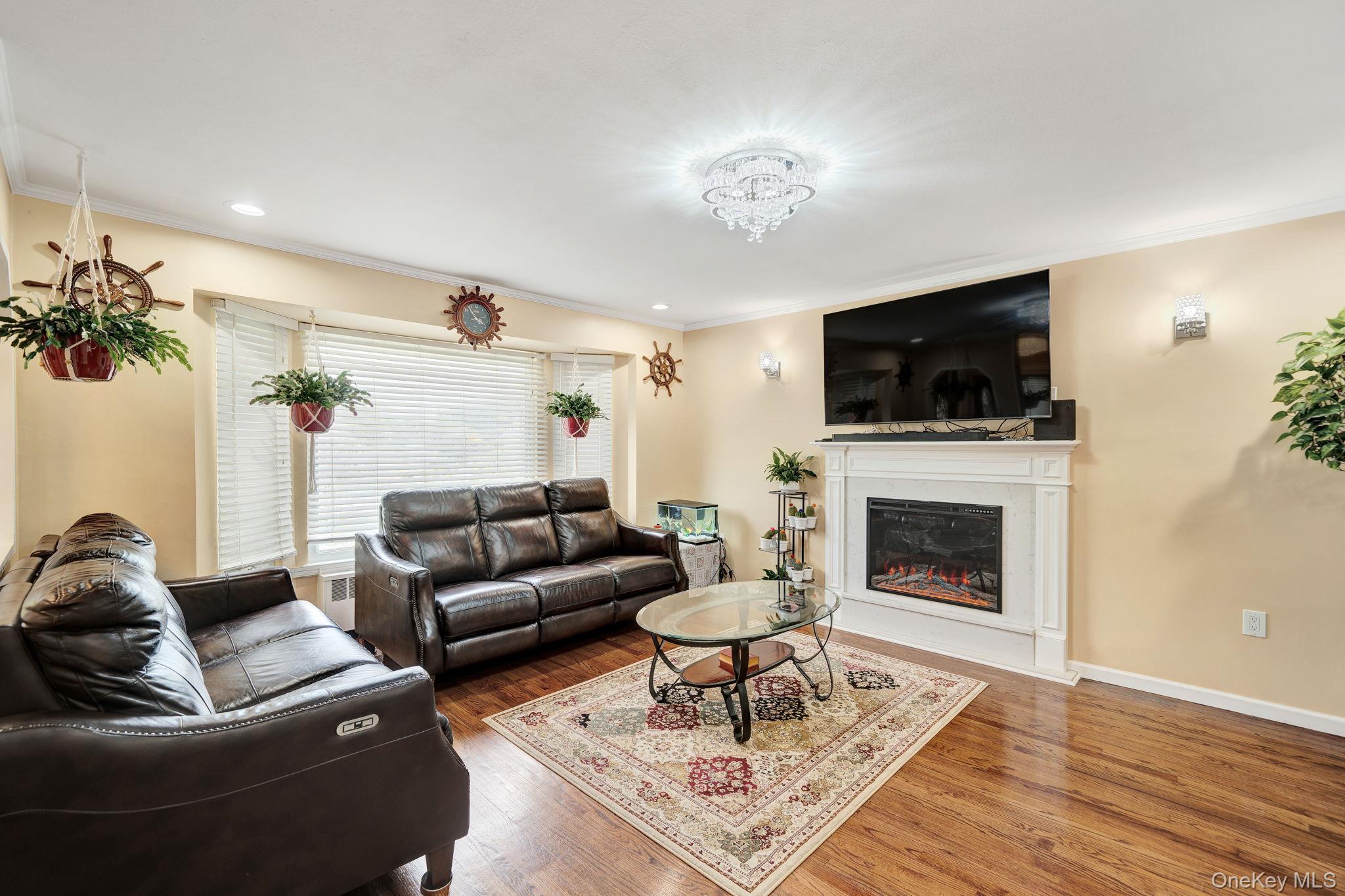1 Wayland Road Plainview, NY 11803 - Photo 8 of 28 Living area featuring ornamental molding, wood finished floors, and a glass covered fireplace