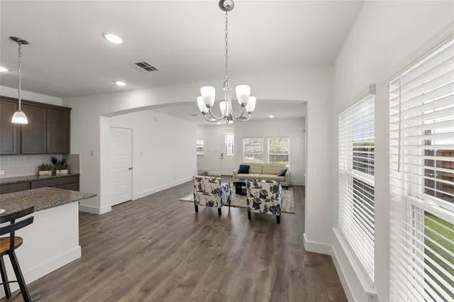 a view of a dining room and livingroom with furniture wooden floor a chandelier