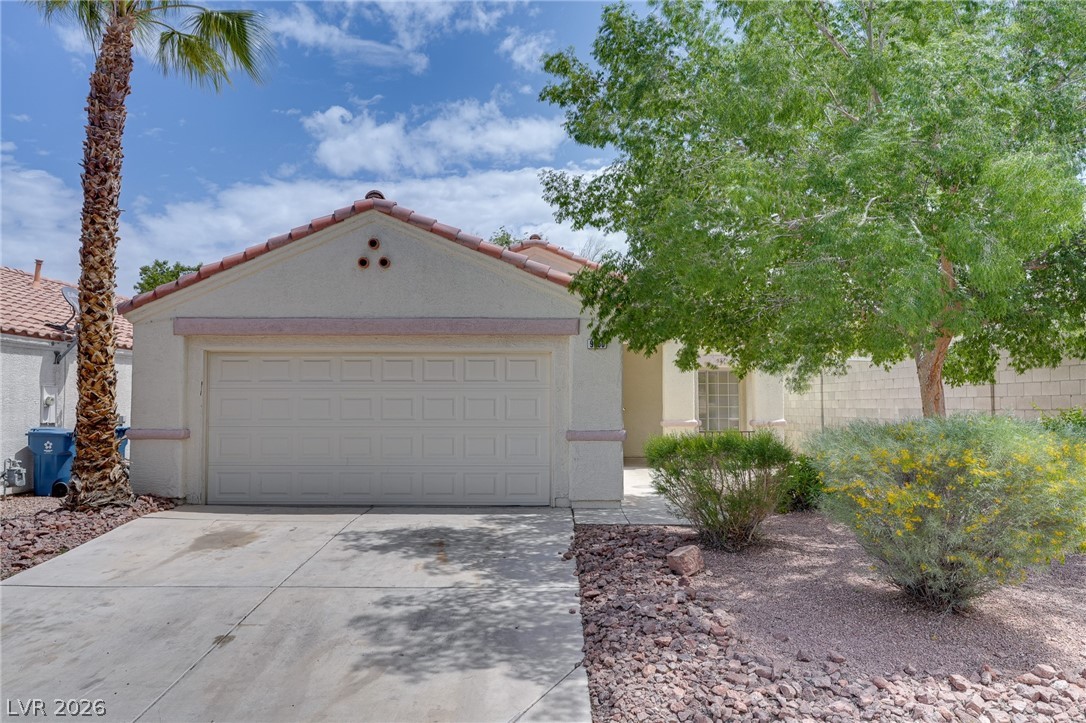 A desert-friendly front yard, boasting a spacious concrete driveway leading to the integrated garage.