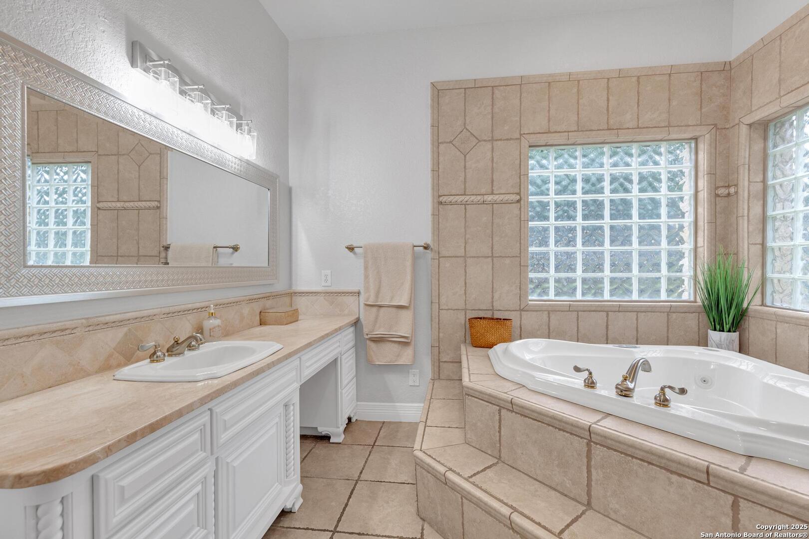 1130 Whispering Water Spring Branch, TX 78070 - Photo 14 of 43 a bathroom with a tub a sink a large mirror and a bathtub next to a window