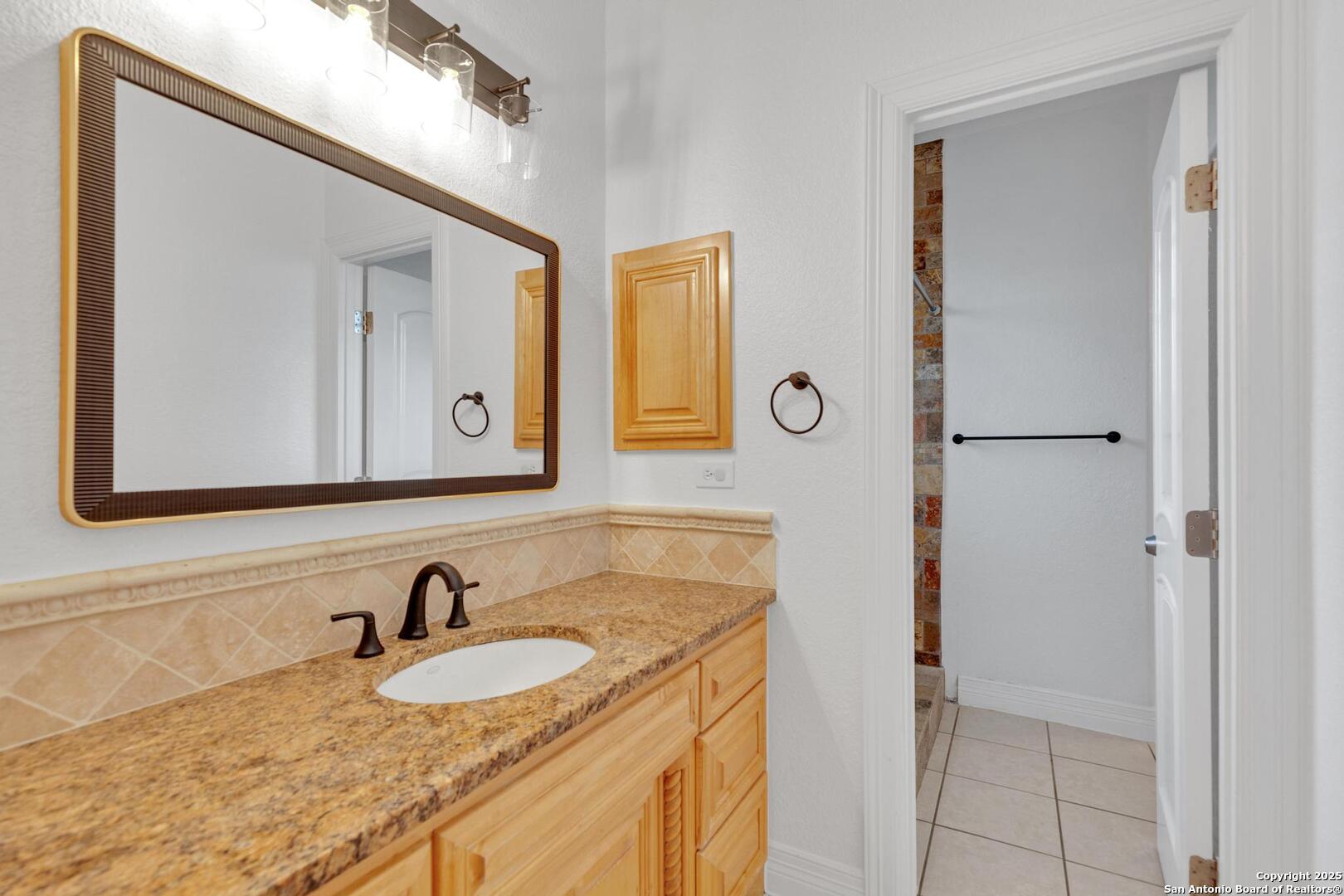 1130 Whispering Water Spring Branch, TX 78070 - Photo 19 of 43 a bathroom with a granite countertop sink and a mirror